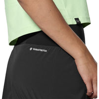 Close-up of black women's athletic skort with Durastretch label, worn with green crop top