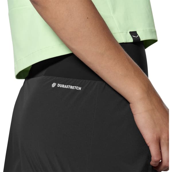 Close-up of black women's athletic skort with Durastretch label, worn with green crop top