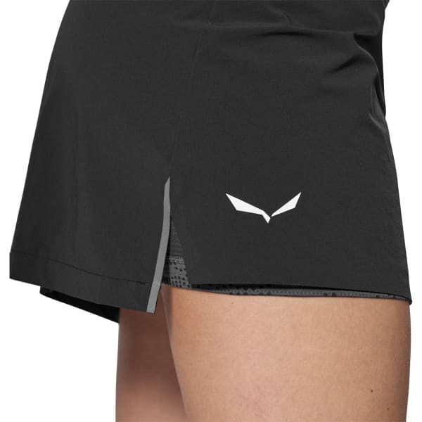 Black athletic skort with inner compression shorts and reflective side stripe, close-up view