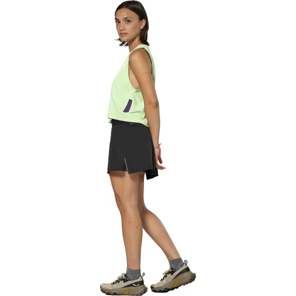 Women's athletic skort in dark black with side slit, paired with lime green tank top, side view