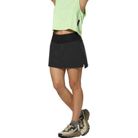 Black athletic skort with wide waistband and side slit, paired with trail shoes, side view
