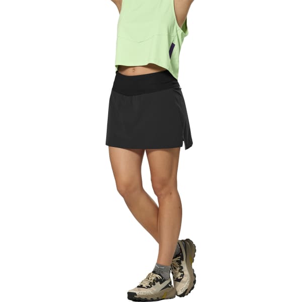 Black athletic skort with wide waistband and side slit, paired with trail shoes, side view
