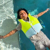 Child wearing bright yellow and white swim vest while floating in swimming pool