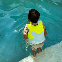 Child wearing bright yellow swim vest with white shark fin design in swimming pool
