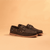 Dark brown nubuck leather boat shoes with lace detail, contrast stitching, and gum sole, three-quarter view