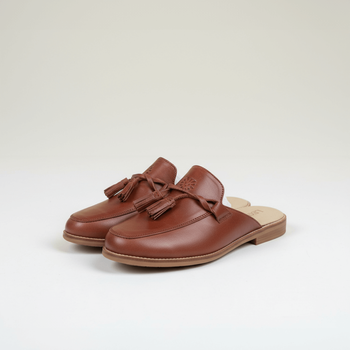 Brown leather tassel mule loafers with flat sole, three-quarter view, backless style