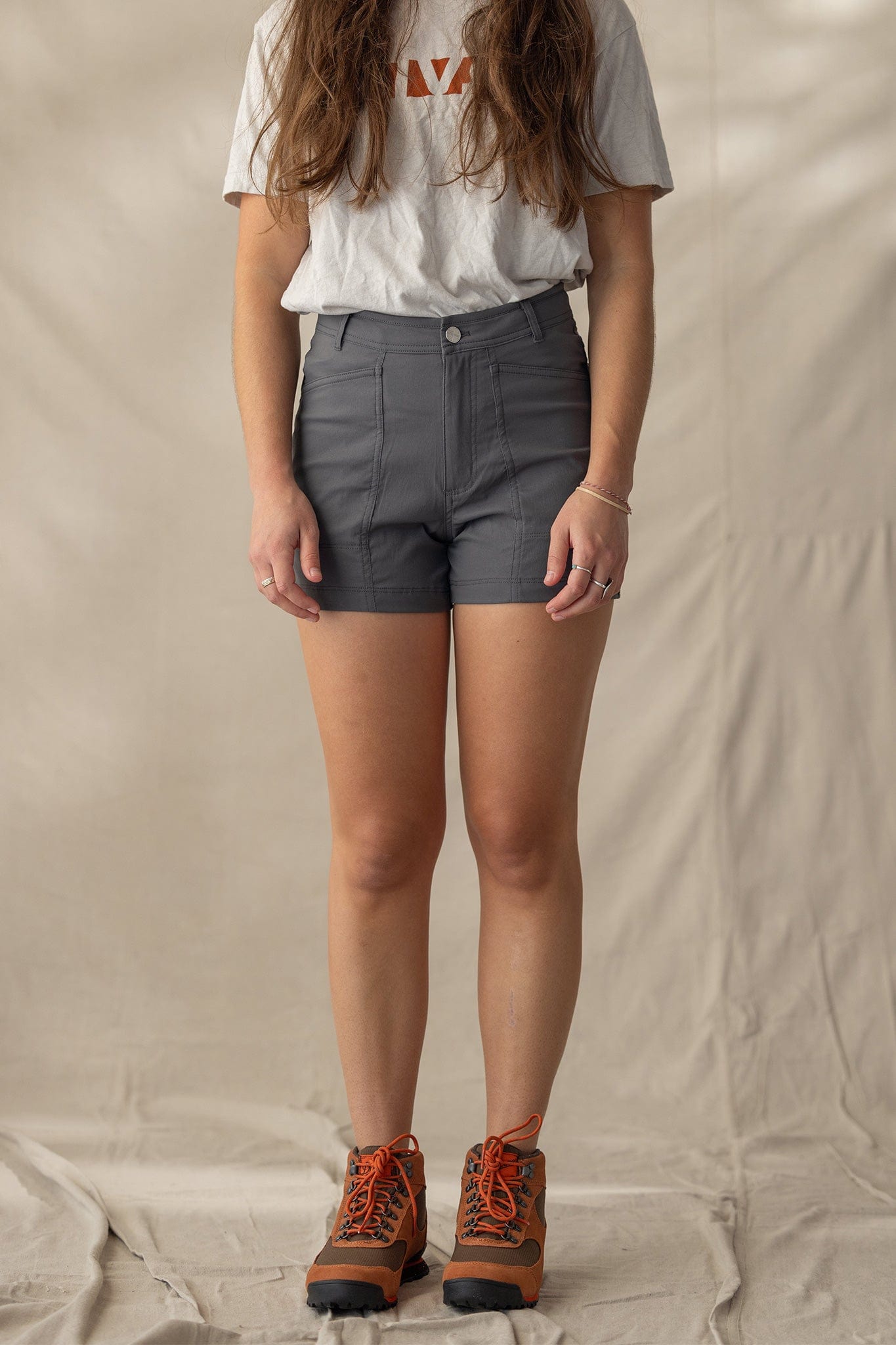 Dark gray high-waisted trail shorts with front pockets, worn with hiking boots