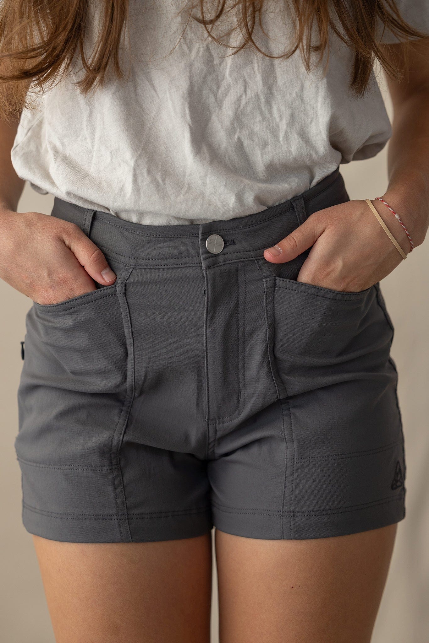Charcoal gray trail shorts with multiple pockets and button closure, worn by woman