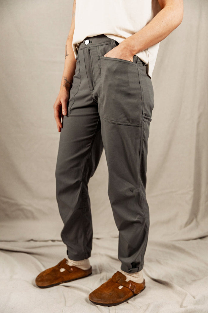 Women's dark gray trail pants with large side pockets, worn with suede clogs, side view