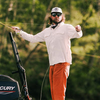 Man wearing rust orange outdoor pants while fly fishing from a boat