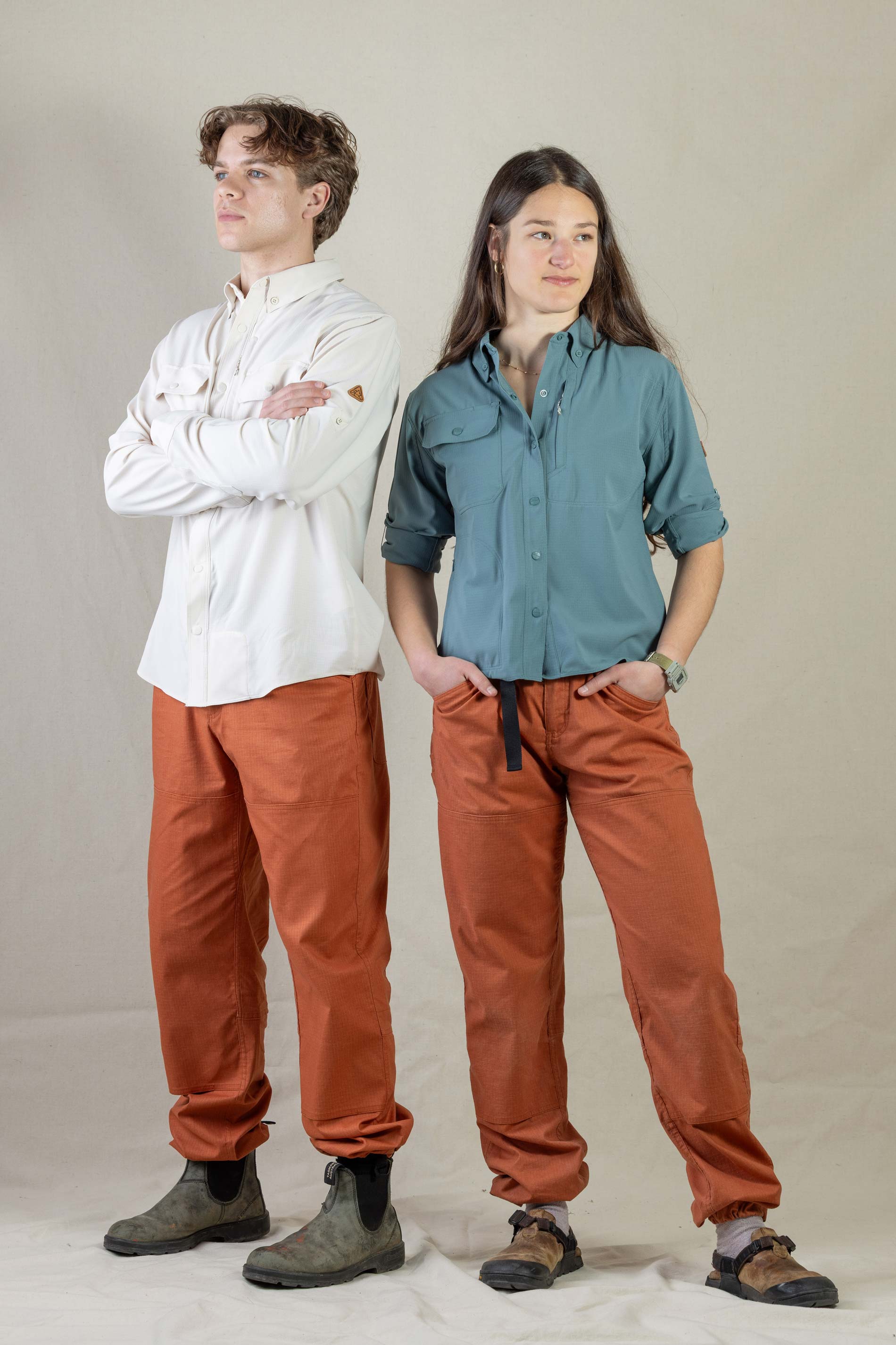 Two models wearing matching rust-colored casual pants with relaxed fit and elastic waistband