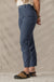 Women's cropped trail pants in dark blue-gray, side view, with snap hem detail and sandals