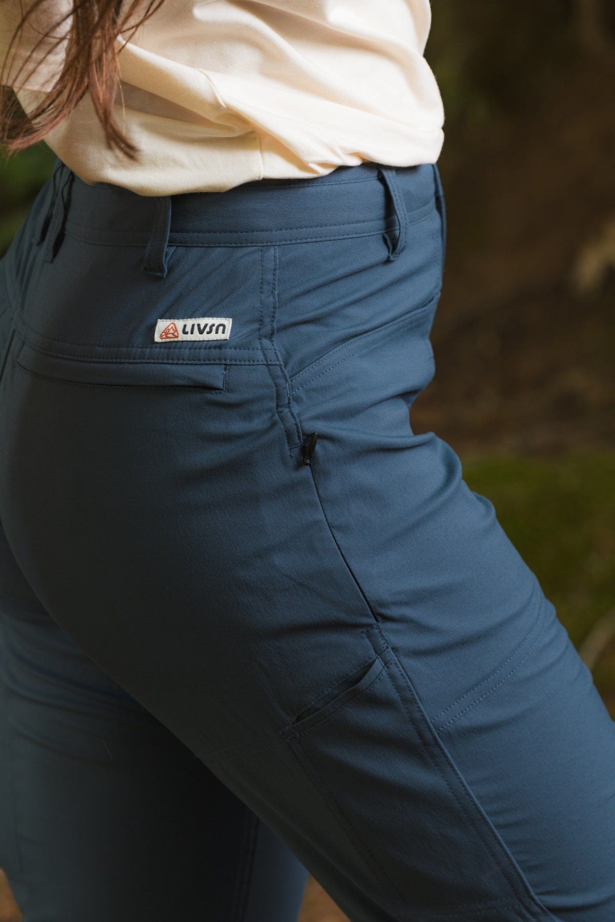 Women's trail pants in dark blue with back pocket detail and brand label, side view