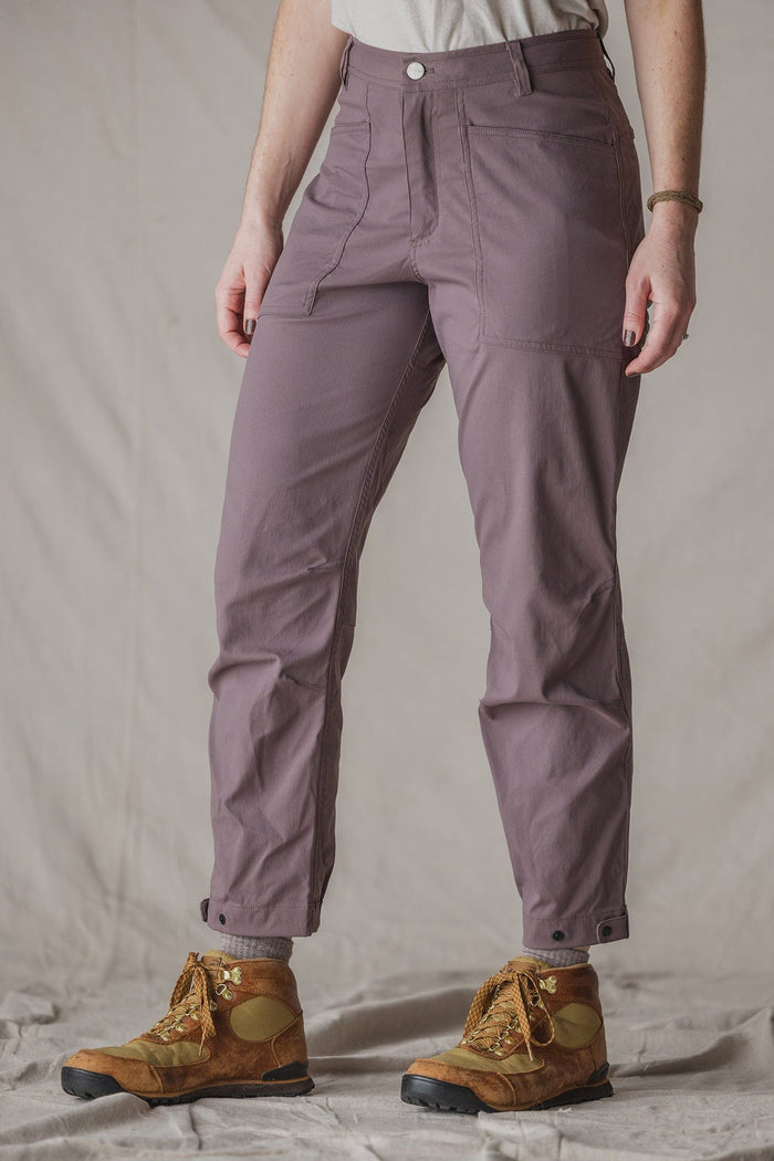Women's trail pants in dusty mauve with front pockets and snap cuffs, paired with hiking boots