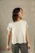 Woman wearing cream colored relaxed fit t-shirt with olive green pants, side profile view