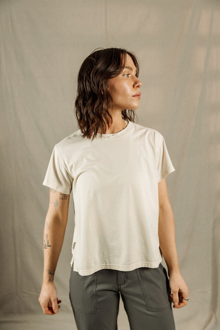 Woman wearing cream colored relaxed fit t-shirt with olive green pants, side profile view