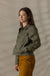 Women's button-front olive jacket with chest pockets and sleeve patch, side view