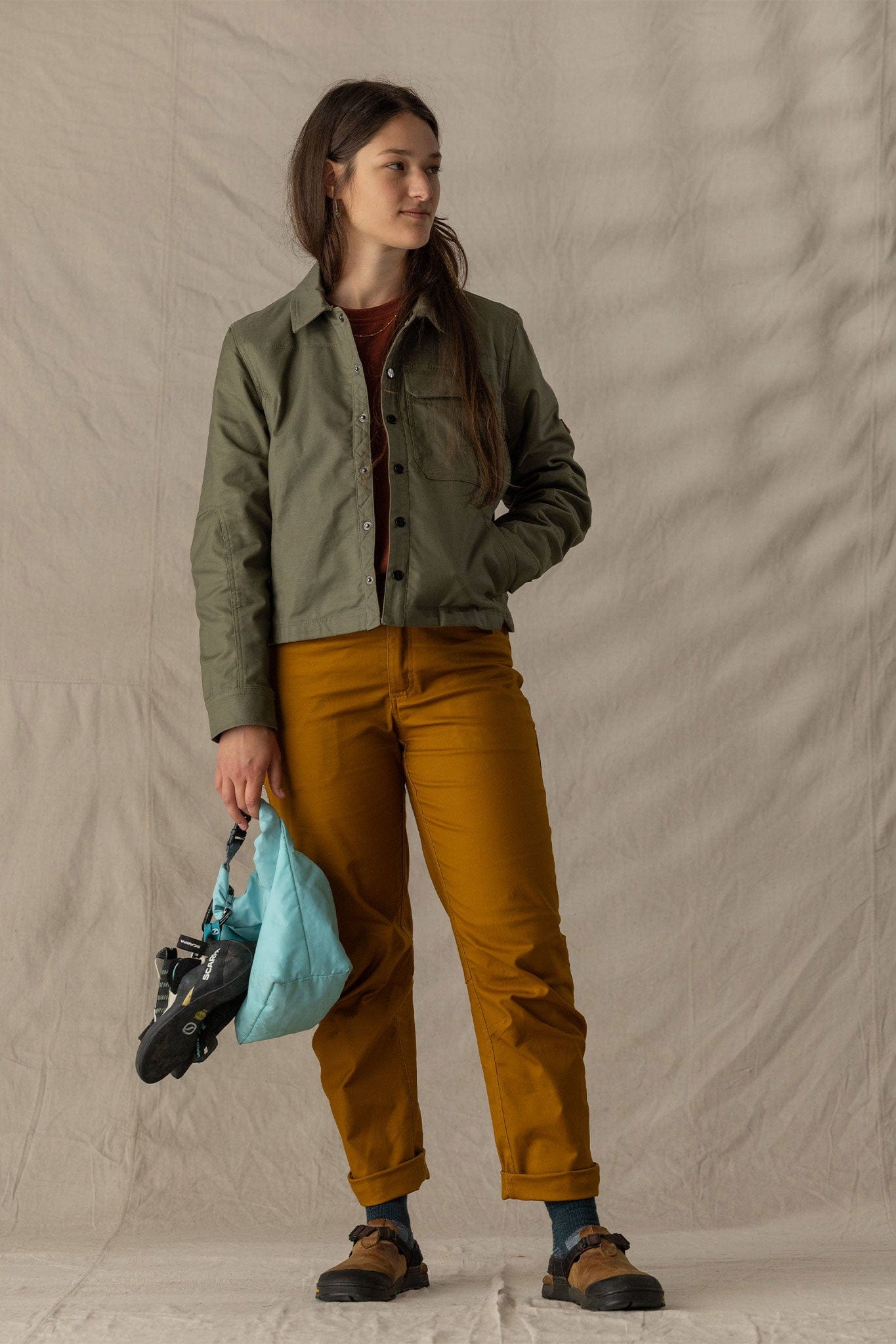 Women's cropped olive button-front jacket with chest pockets, worn over mustard pants, front view