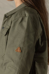 Close-up detail of olive green women's jacket sleeve with leather triangle brand patch