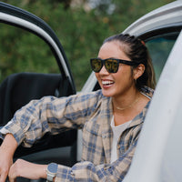 Woman wearing black sunglasses with mirrored lenses leaning out of white car door