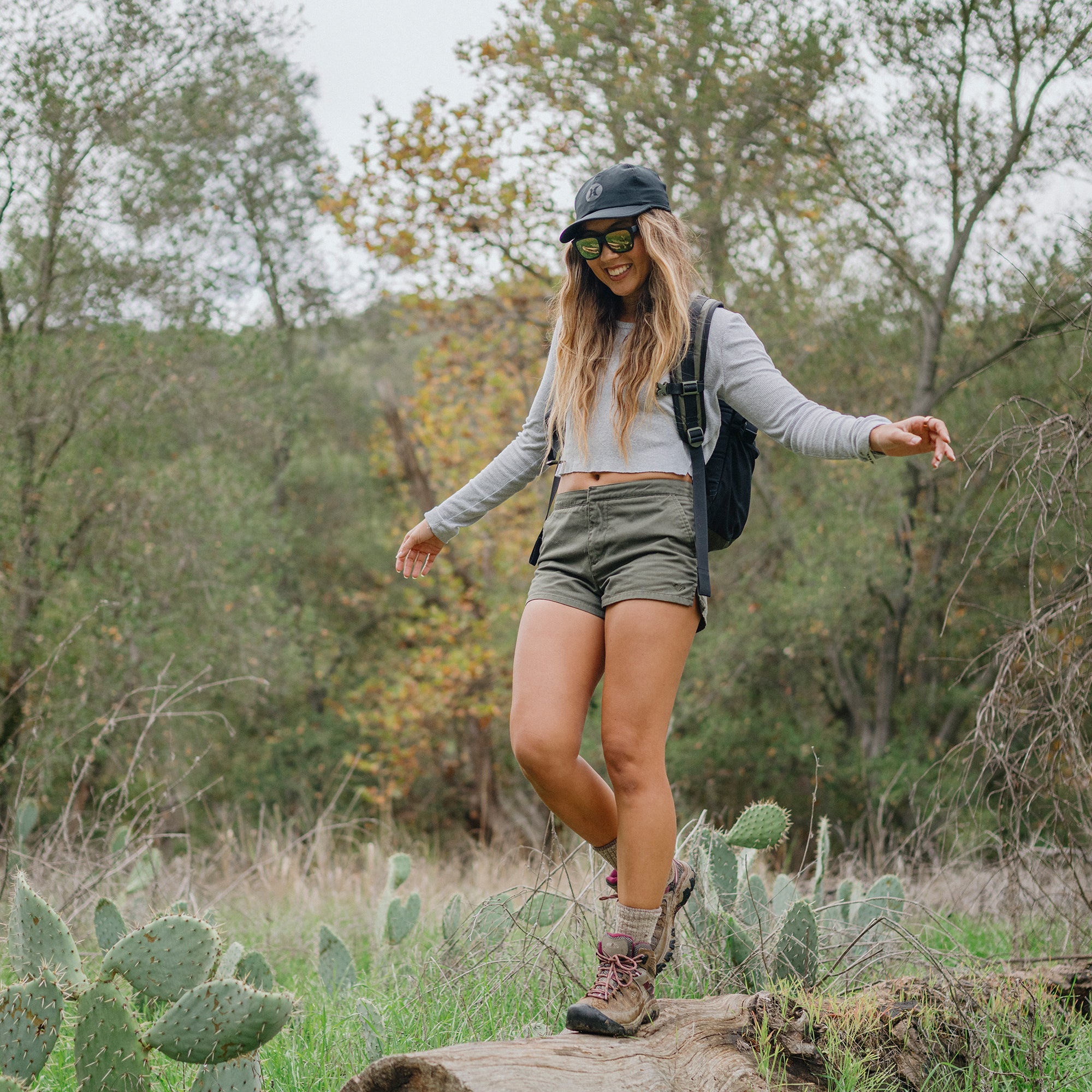 Woman wearing black sunglasses with reflective lenses hiking outdoors in natural setting