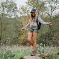Woman wearing black sunglasses with reflective lenses hiking outdoors in natural setting