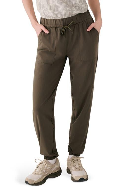 Olive green jogger pants with drawstring waist and side pockets, worn with sneakers