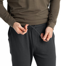Close-up detail of men's jogger waistband with drawstring being adjusted by both hands