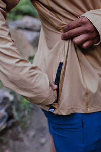 Man wearing brown zip-up hoodie with blue pants, showing interior pocket detail