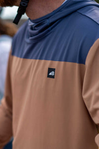 Color-blocked hooded sun shirt with navy blue top panel and brown bottom panel, worn outdoors