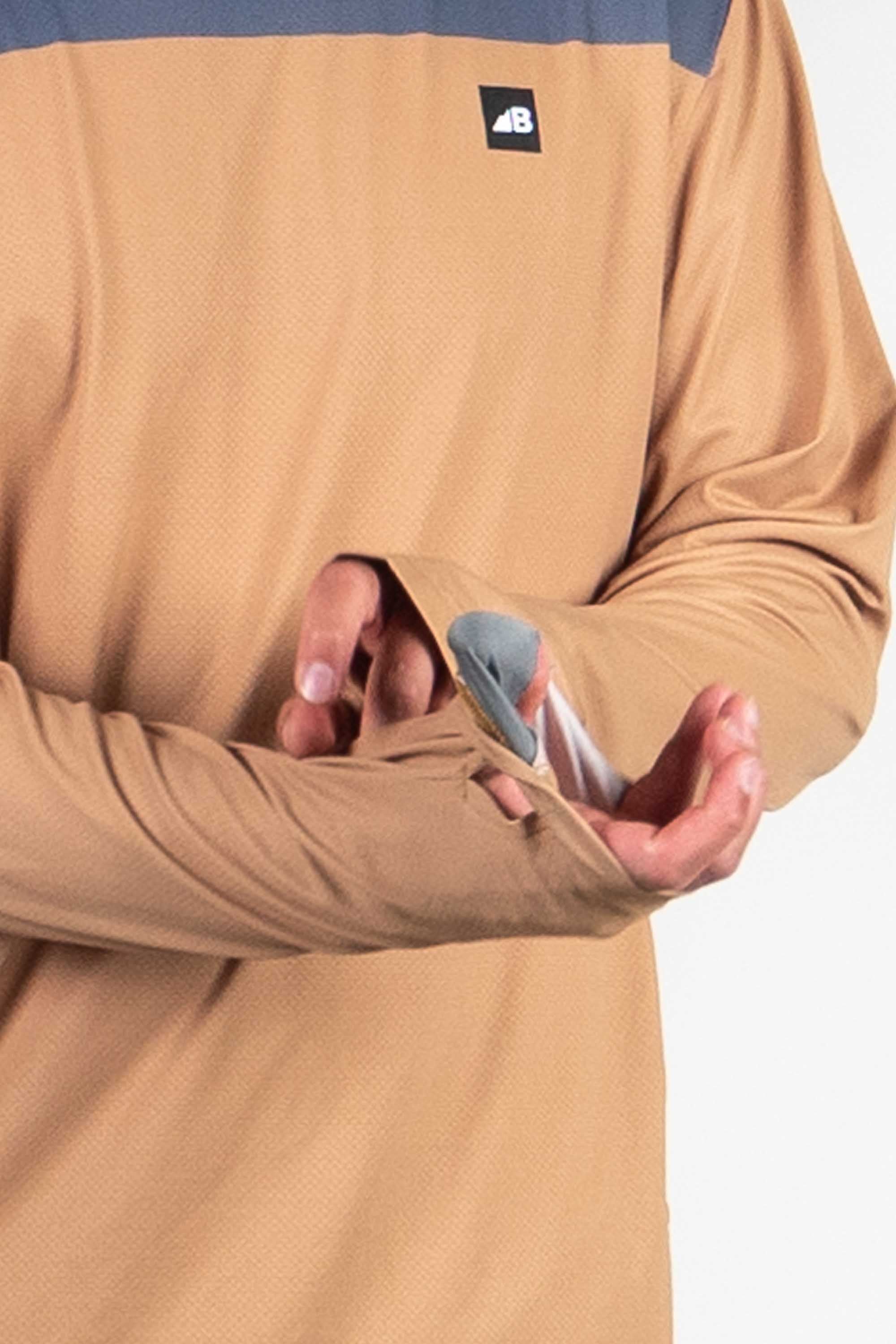 Person wearing tan hoodie with blue accents holding sunglasses cleaning cloth