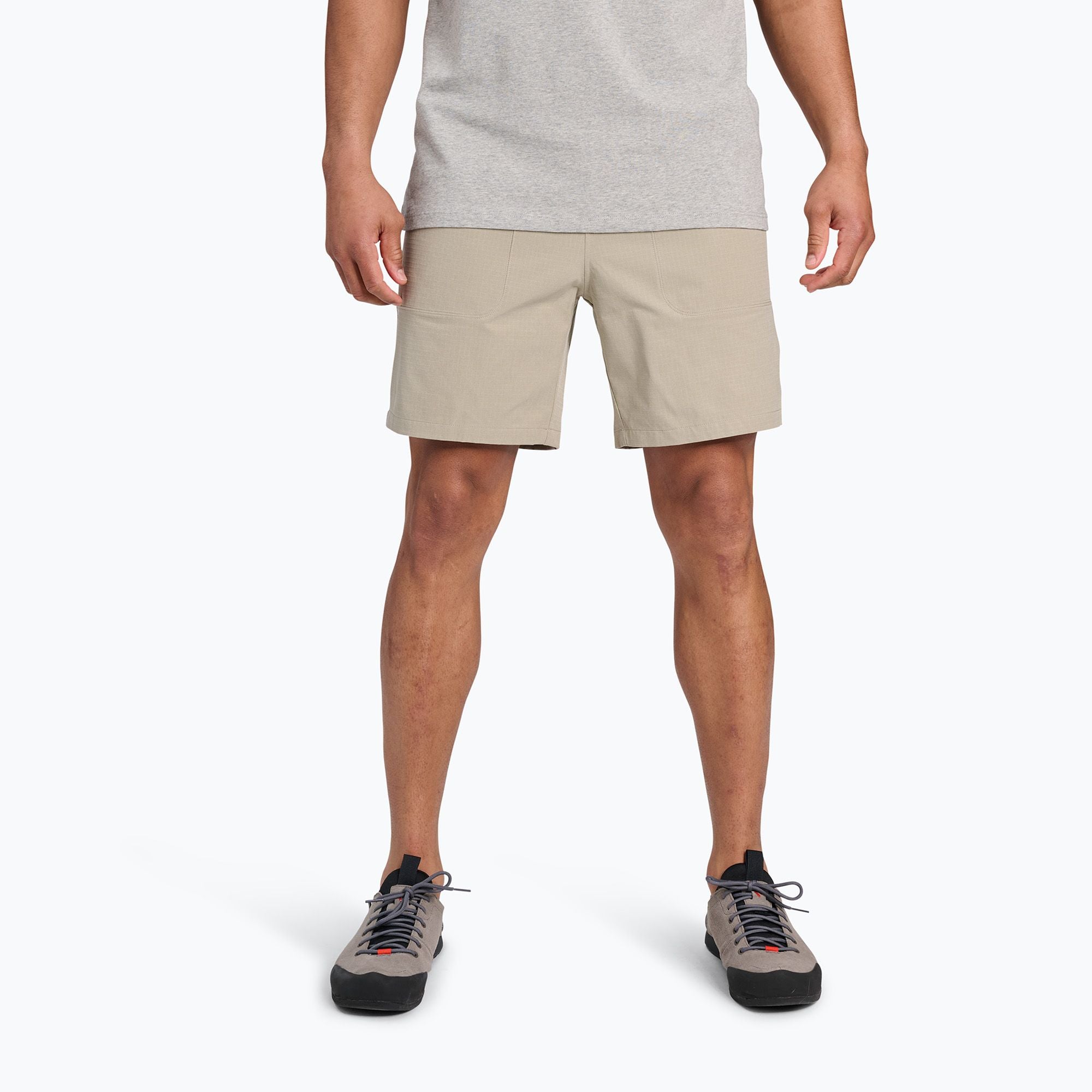 Light beige athletic shorts on model, front view, paired with hiking shoes