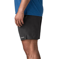 Black athletic shorts with elastic waistband worn by person, side view showing fit