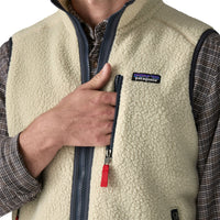 Close-up detail of cream sherpa fleece vest with navy zipper, red pull tab, and brand logo patch