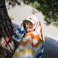 Multi-colored striped towel with wavy pattern wrapped around person outdoors
