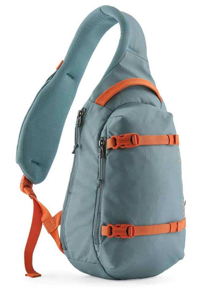 Single-strap sling bag in teal with orange buckles and compression straps, side angle view