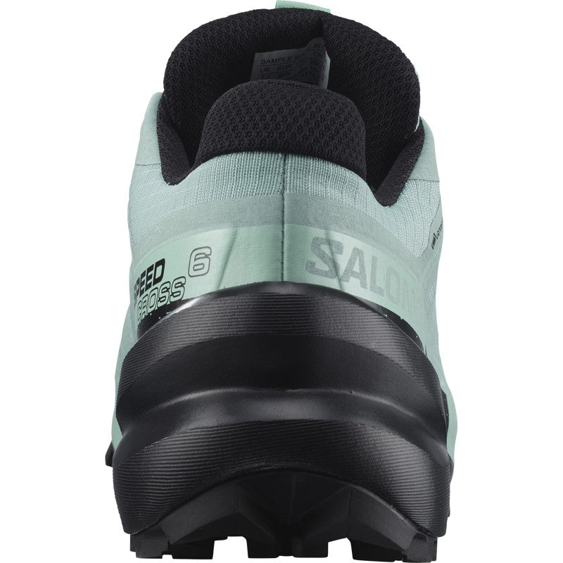 Trail running shoe rear view showing aqua green upper, black lugged outsole, and ankle collar