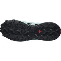 Trail running shoe sole view showing aggressive black lug pattern with mint green upper