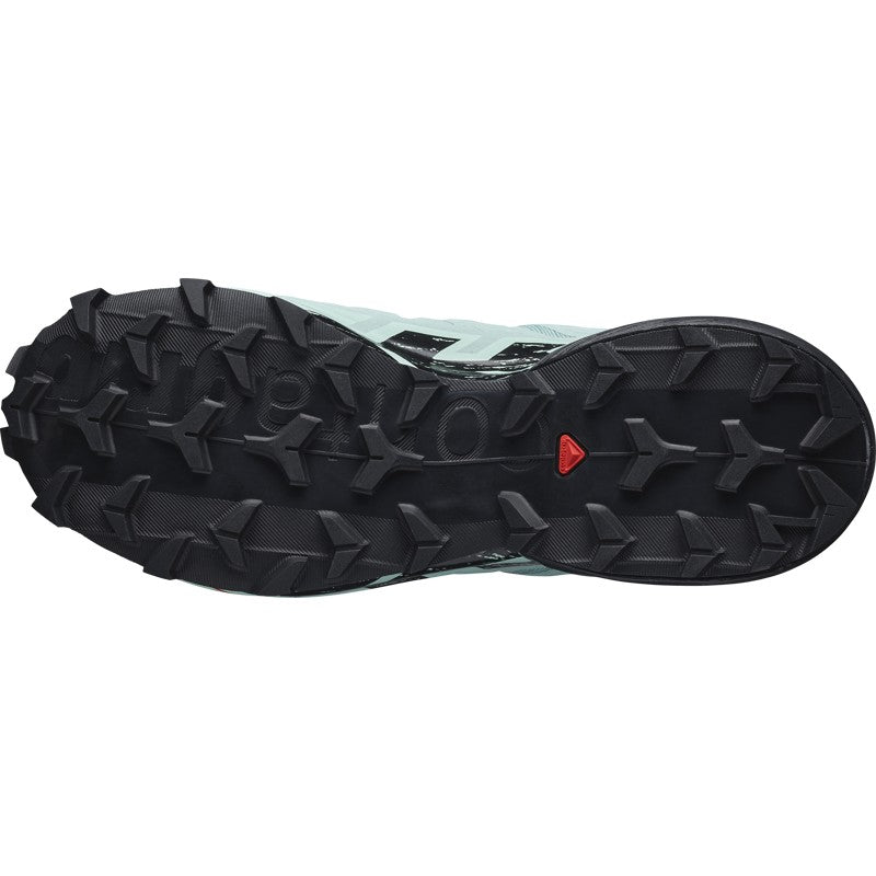 Trail running shoe sole view showing aggressive black lug pattern with mint green upper