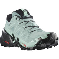Women's trail running shoe with mint green upper, black aggressive lug outsole, and Gore-Tex waterproof construction
