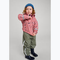 Toddler wearing pink patterned rain jacket with hood, olive rain pants, and navy boots