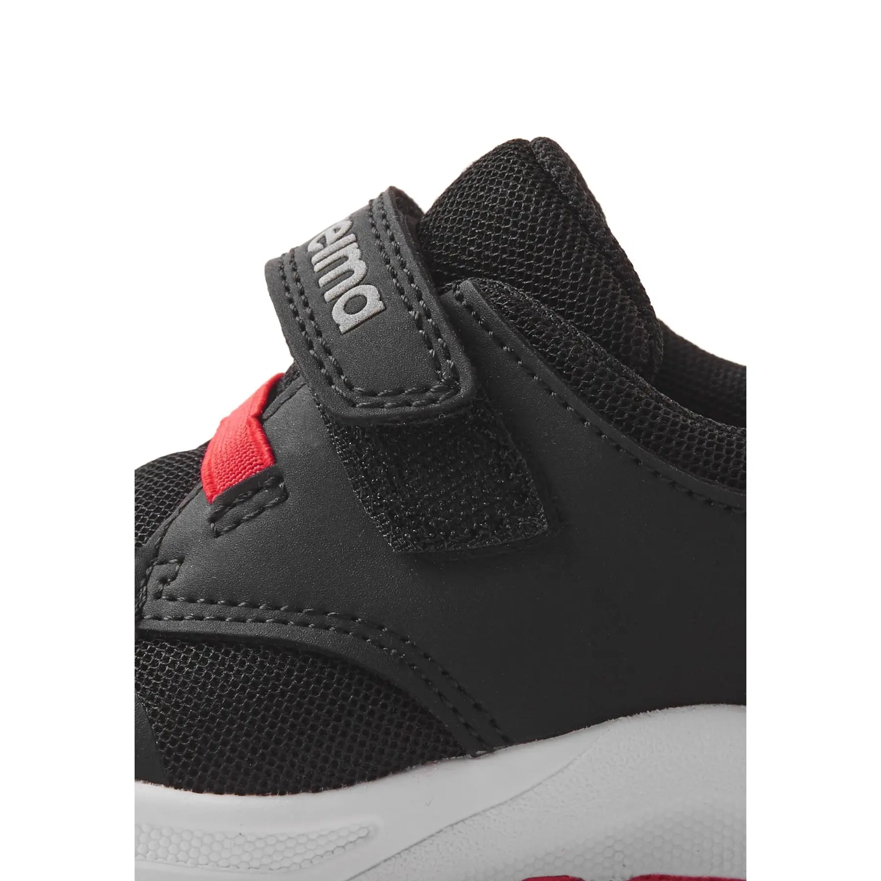 Black children's sneaker with velcro strap and mesh details, side view closeup
