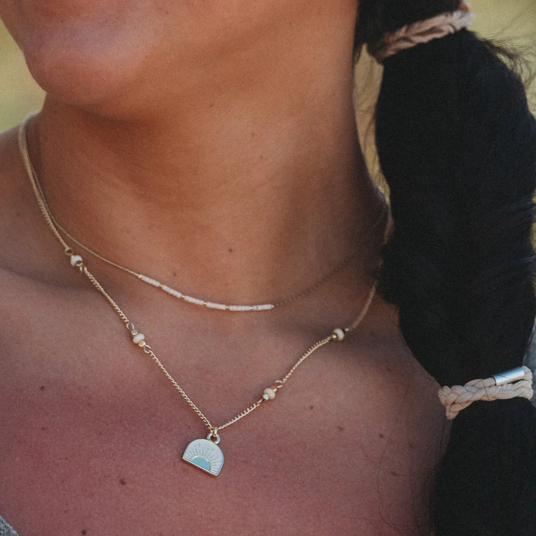 Layered necklace set with beaded choker and gold chain pendant featuring a sunrise enamel charm