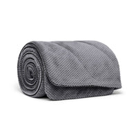 Large fleece blanket rolled up, showing textured diamond pattern in dark grey, studio view