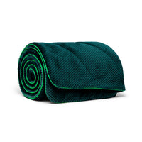 Rolled fleece blanket in deep teal with bright green trim, showing textured fabric detail