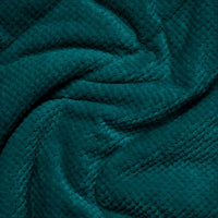 Close-up detail of a textured fleece blanket in deep teal, showing fabric drape and weave pattern