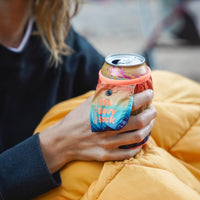 Hand holding a canned beverage wrapped in a colorful gradient fabric can cooler sleeve
