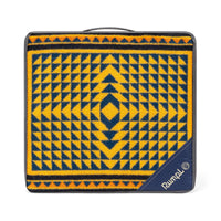 Folded geometric patterned blanket in gold and navy with diamond motif, shown in travel carry case