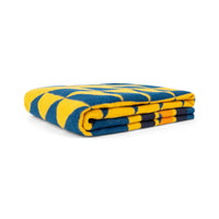 Folded soft wool blanket with bold yellow and blue geometric quilted pattern, studio view