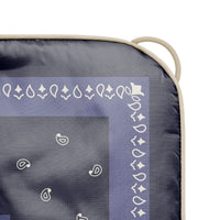 Close-up corner detail of a puffy blanket with bandana paisley print and cream binding edge